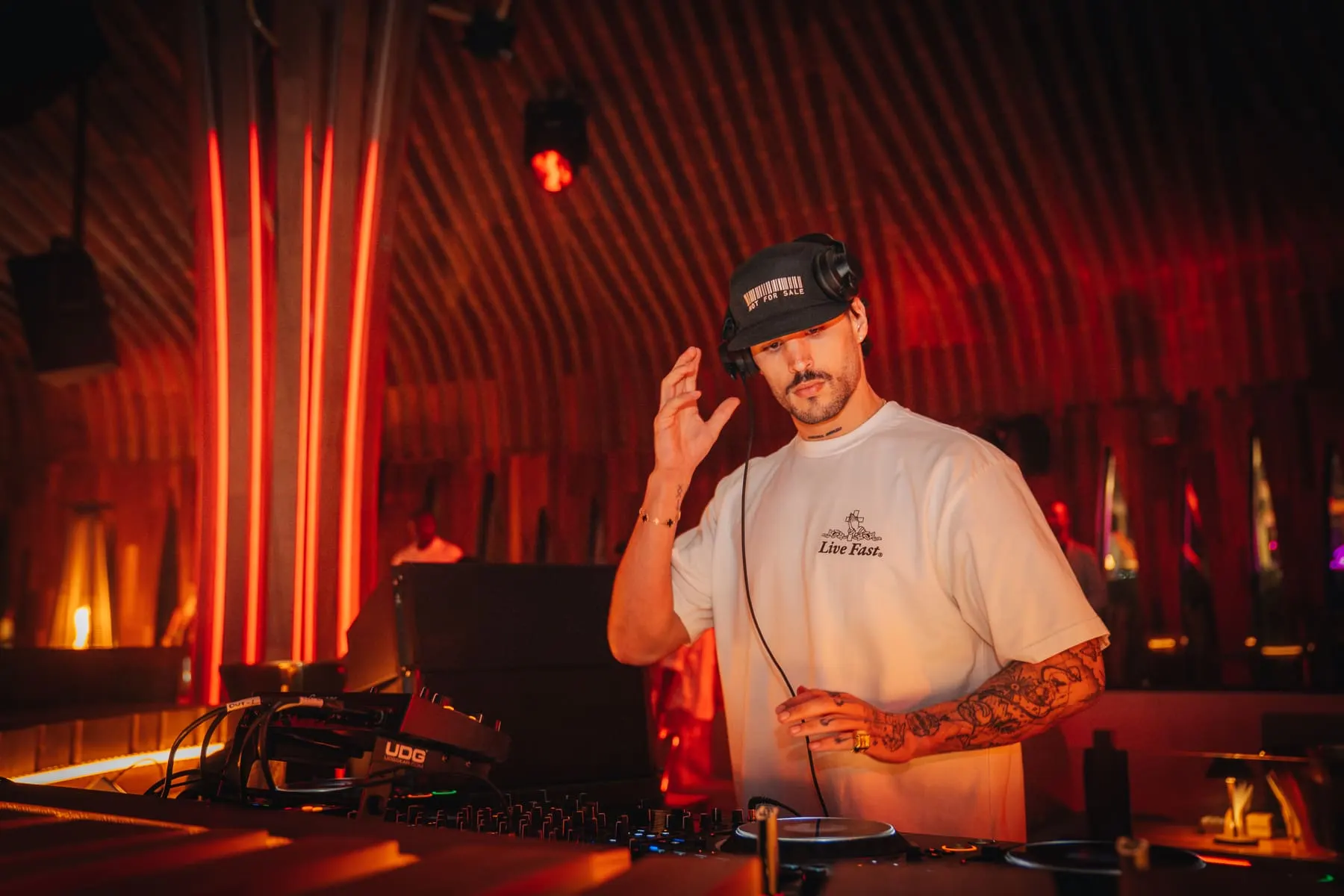 DJ in a white cap at the decks, red light columns behind — FIVE Bohemia — Loco Dice, Dubai — Agency Verse