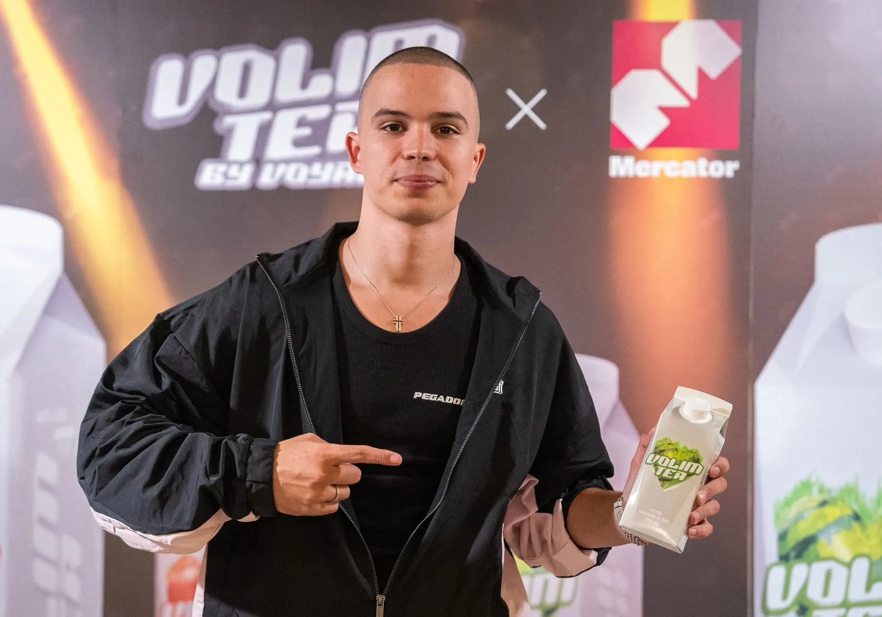 Presenter holding a Volim Tea bottle at the launch — Voyage × Volim Tea, Mercator, Slovenia — Agency Verse